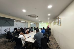 A group of people sitting at a table listening to the presenter